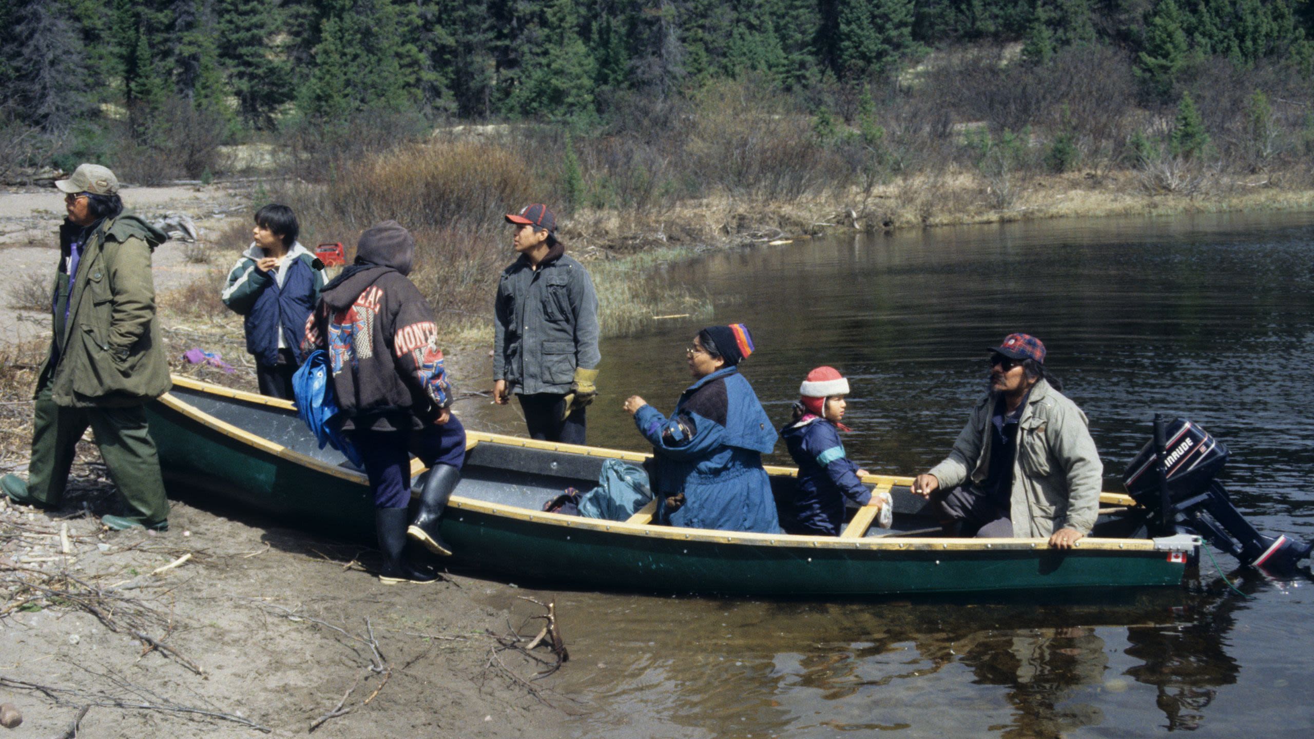Innu family in and standing beside a canoe