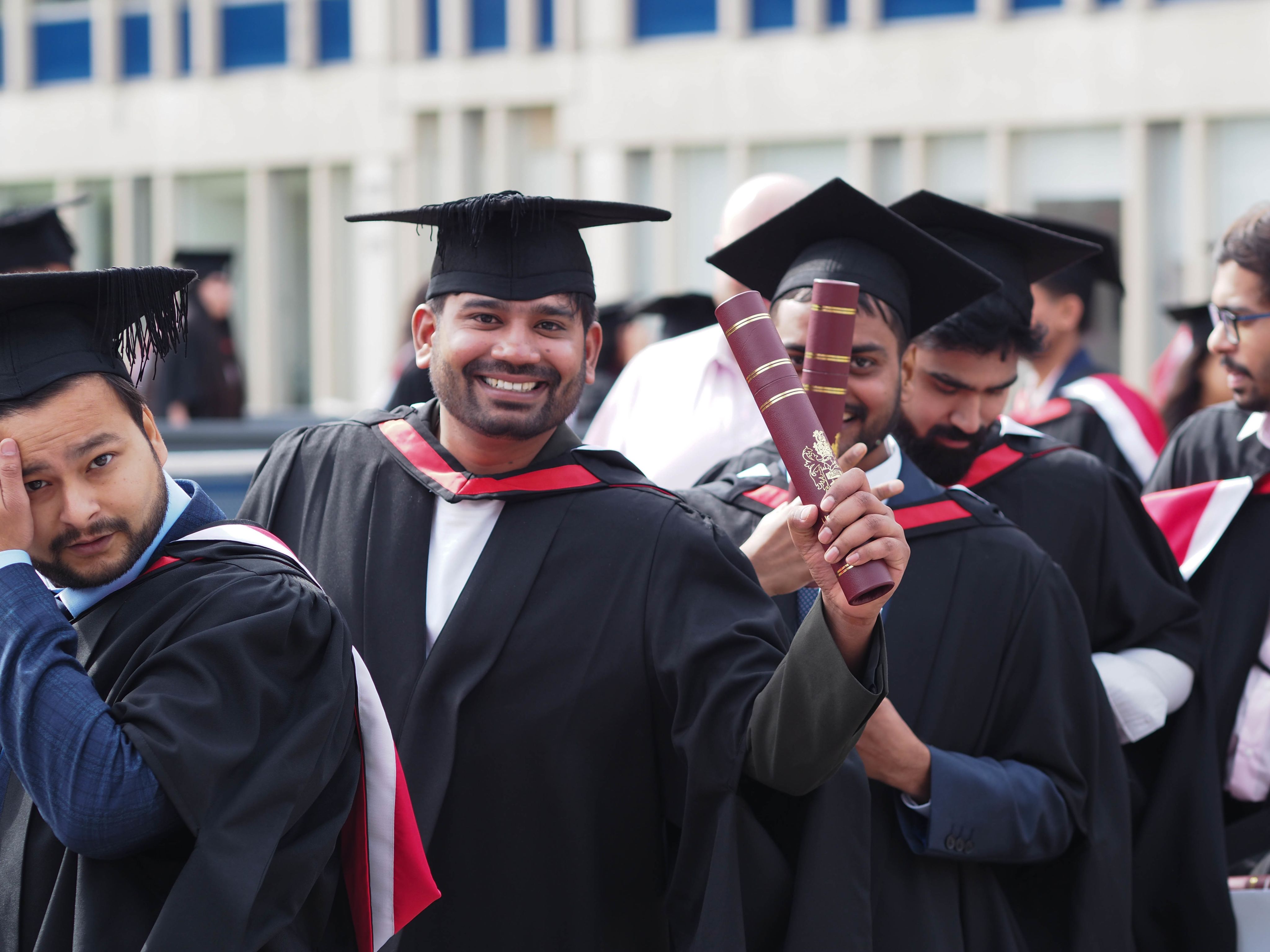 A woman, smiling, adjusts a graduate's academic gown