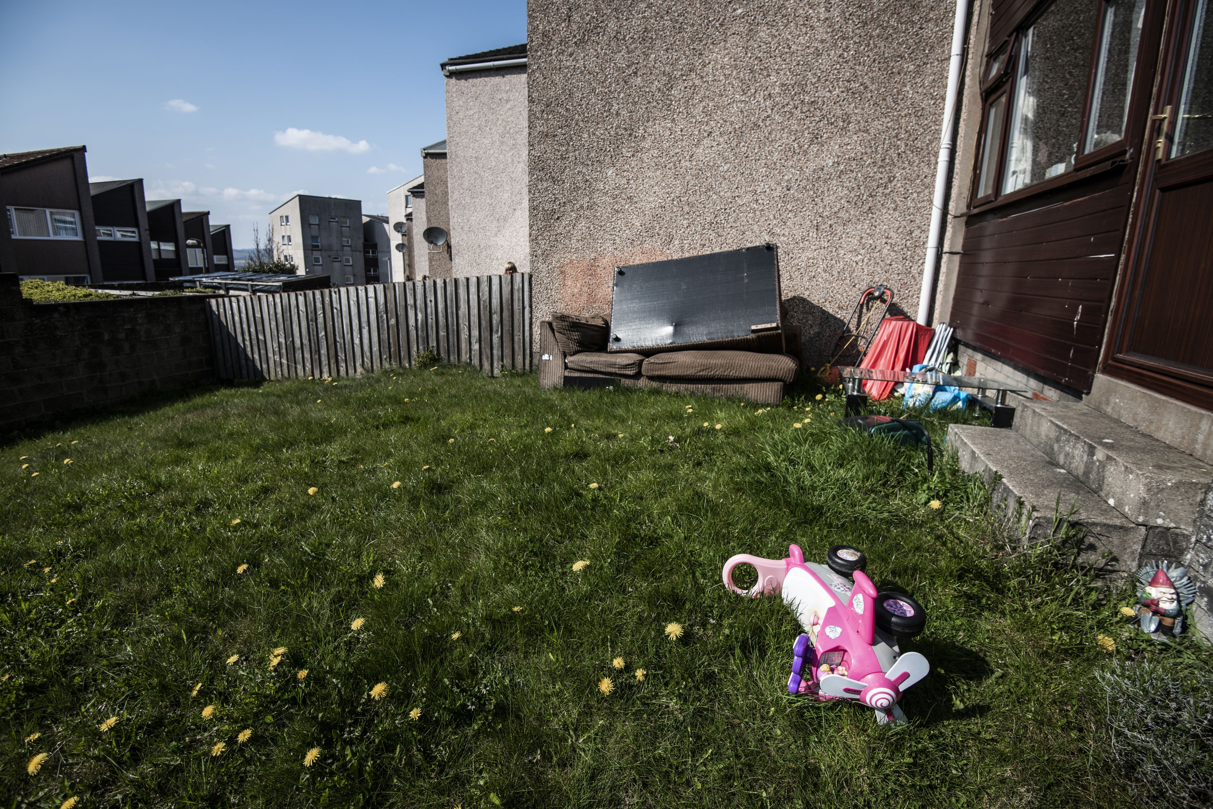 The garden of a home showing a sofa and other household items disposed of