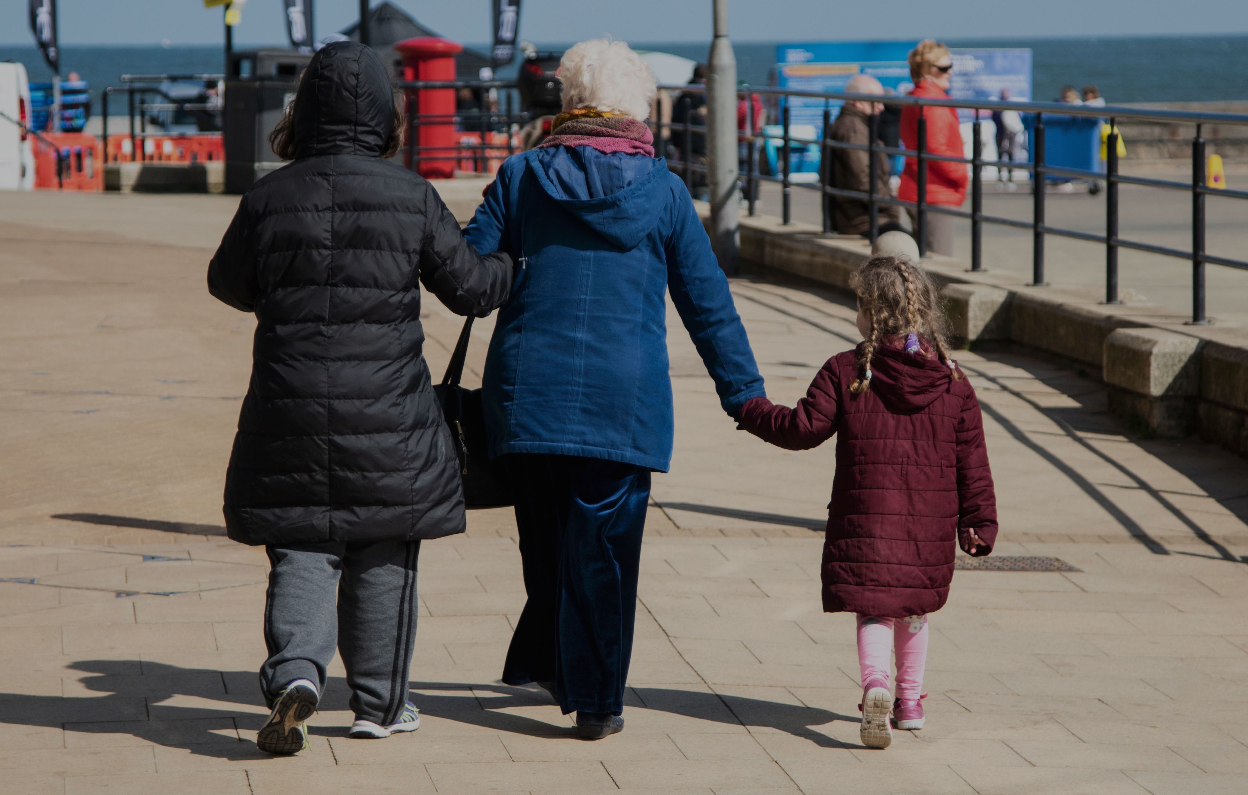 2 adults and a child walking through the street with their back to the camera