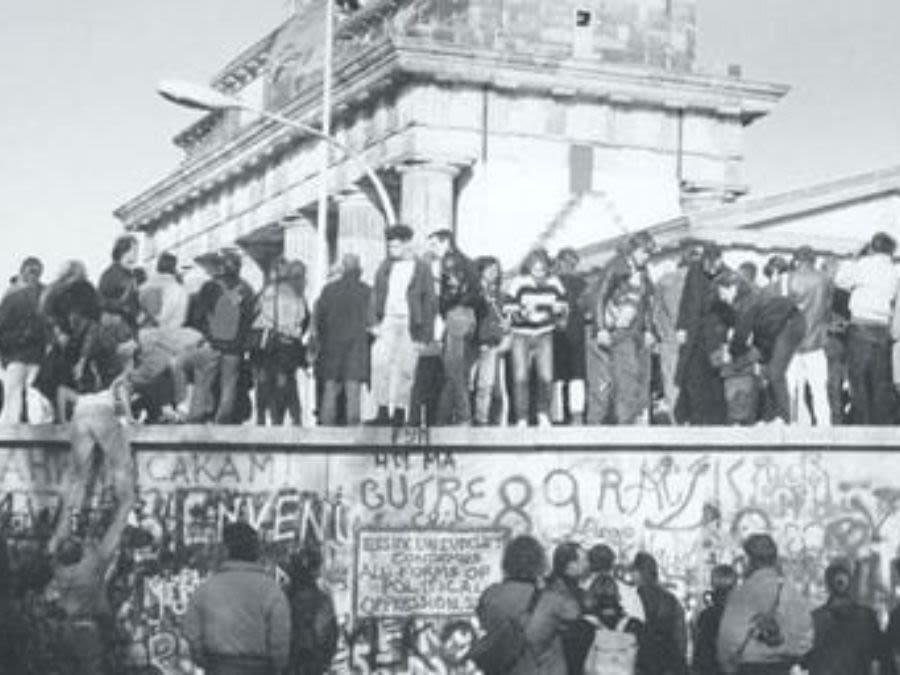 People standing atop the Berlin Wall.