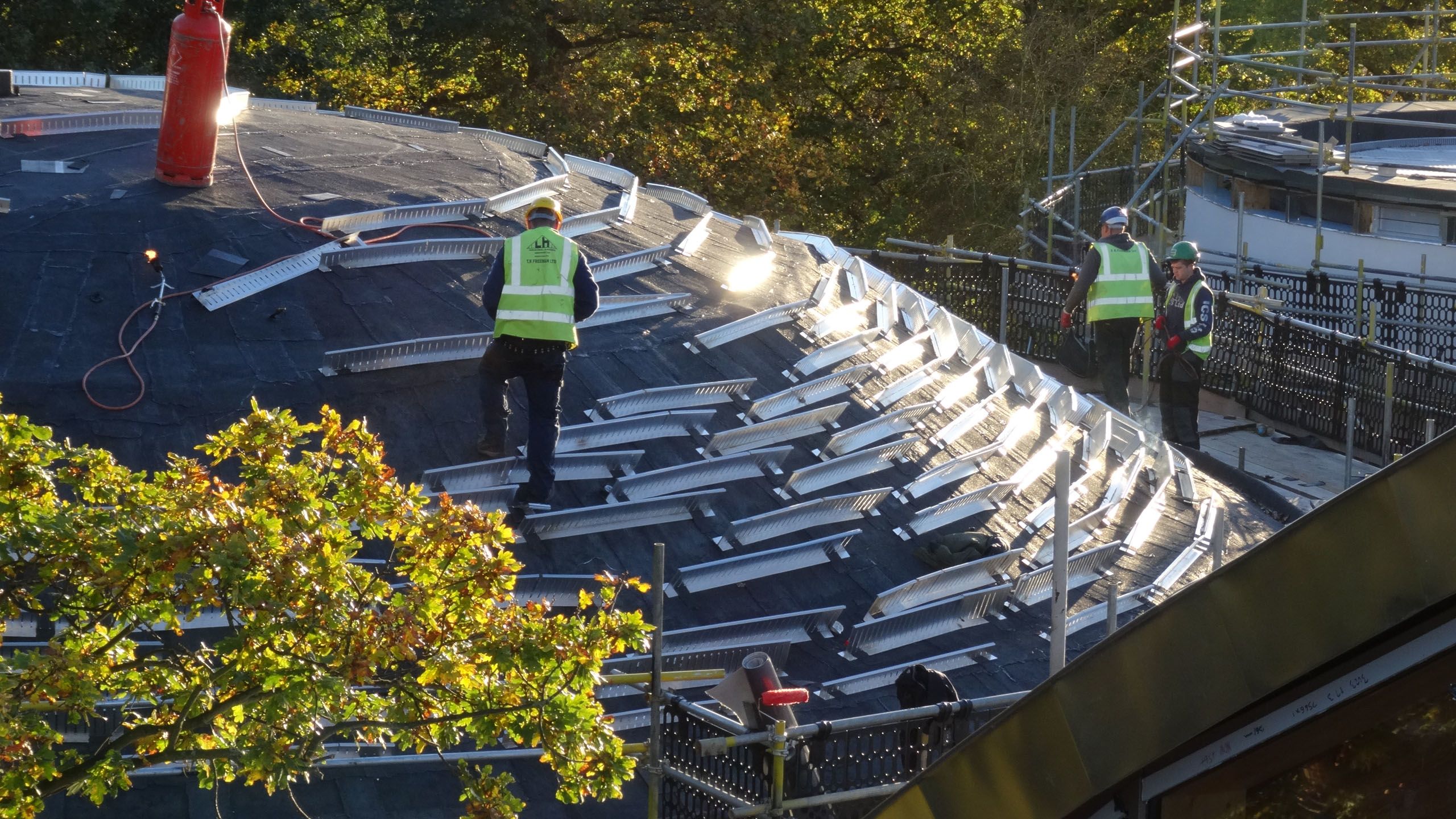 Construction workers ready a roof for installation of greenery in the low sun.