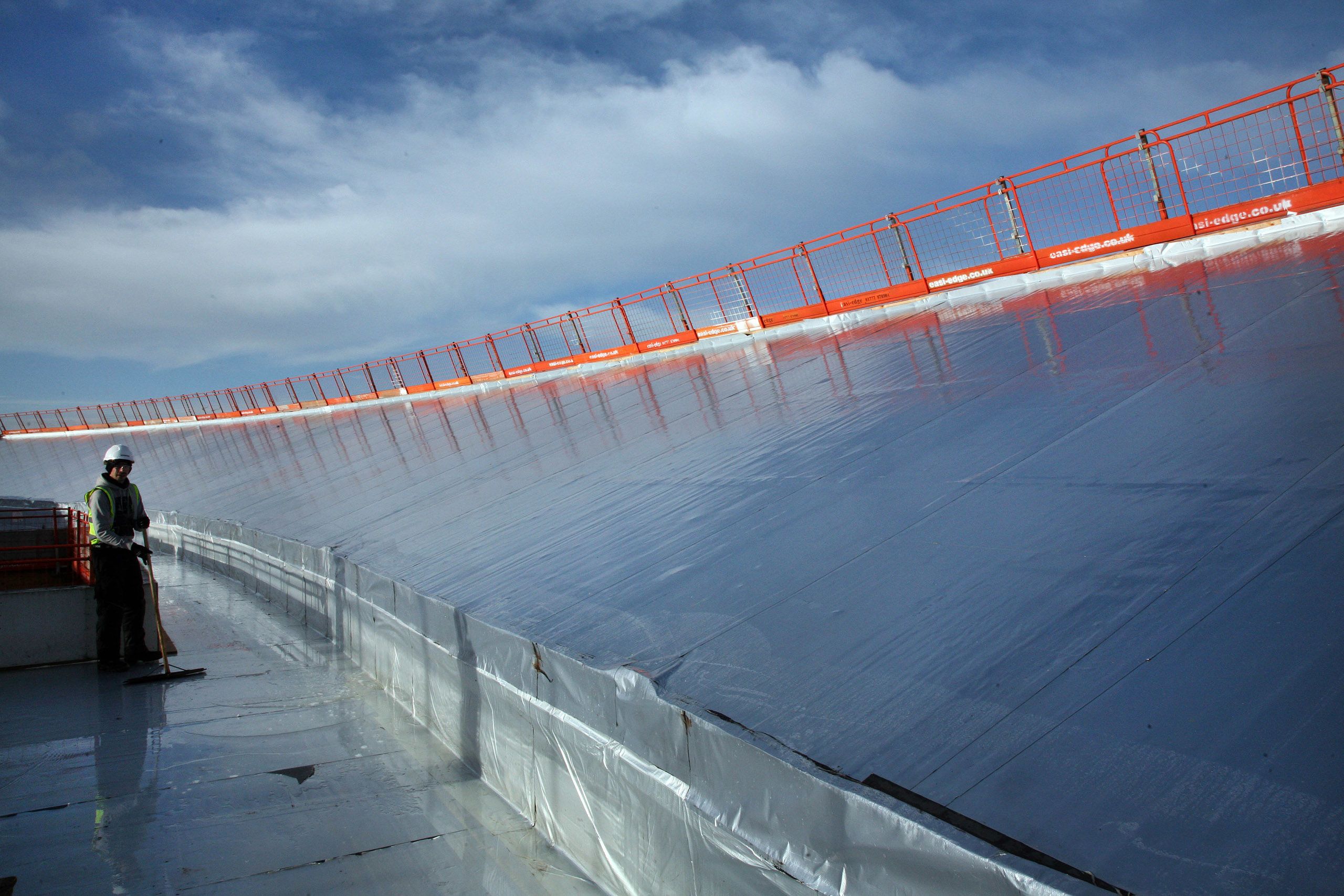 The surface of a wide, sloping bank shines under the sun before its solar panels are installed.
