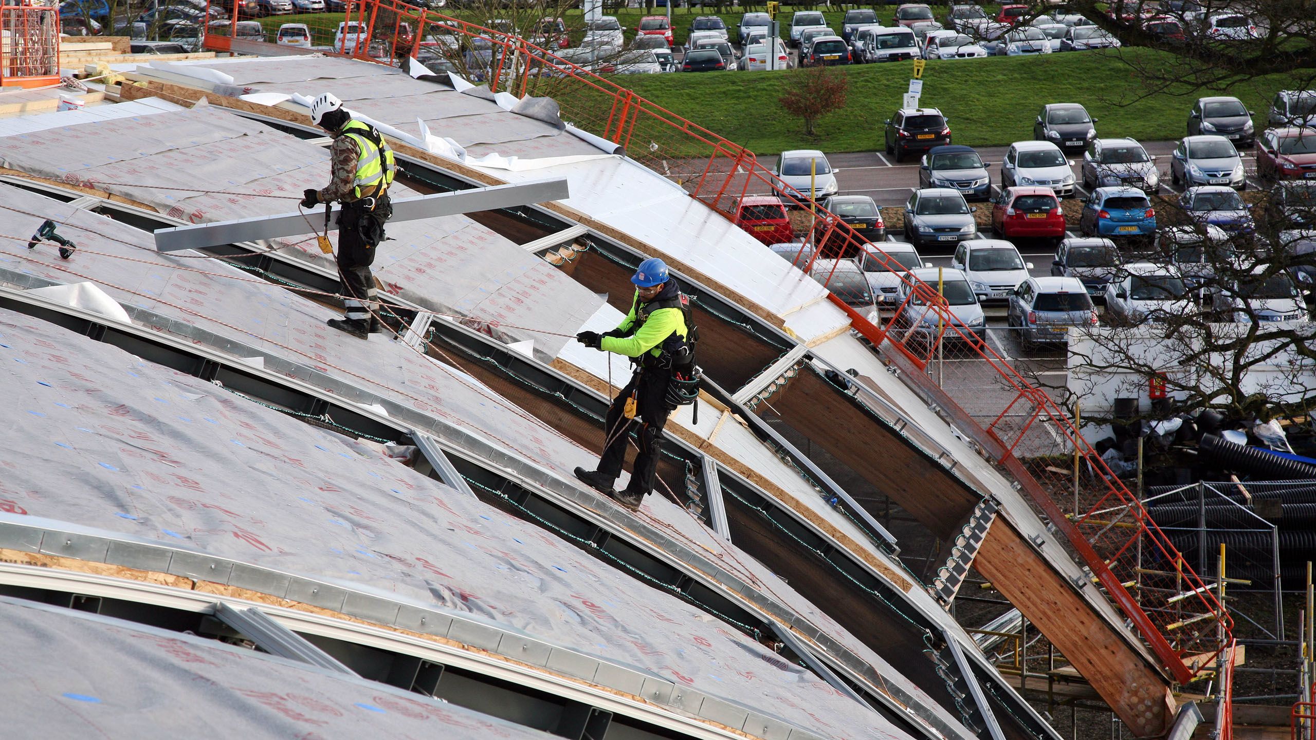 A construction worker abseils down the outside of EBS' incomplete arching roof.