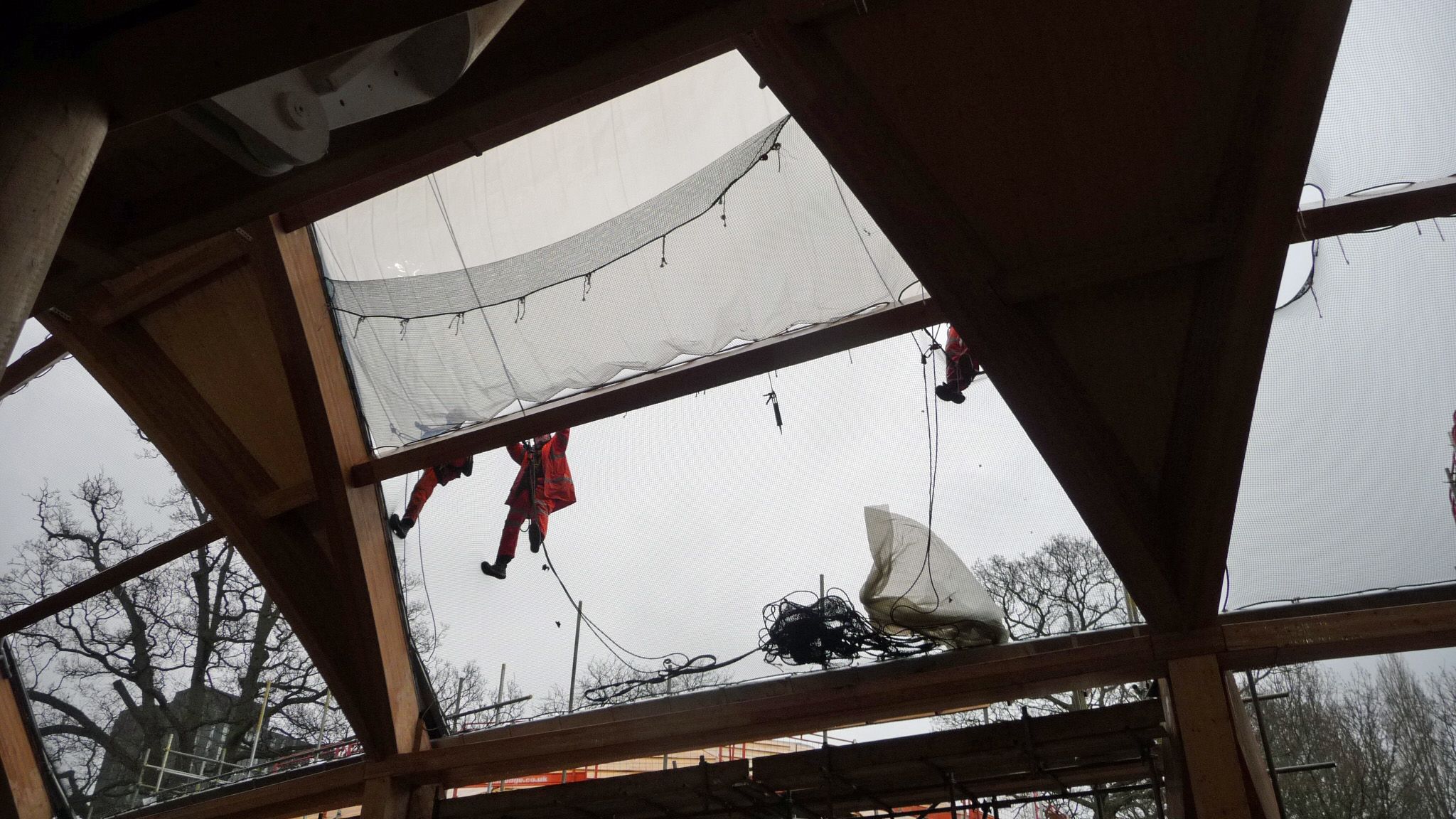 Construction workers appear to levitate as they stand on a mesh to assemble the windows of EBS' roof.