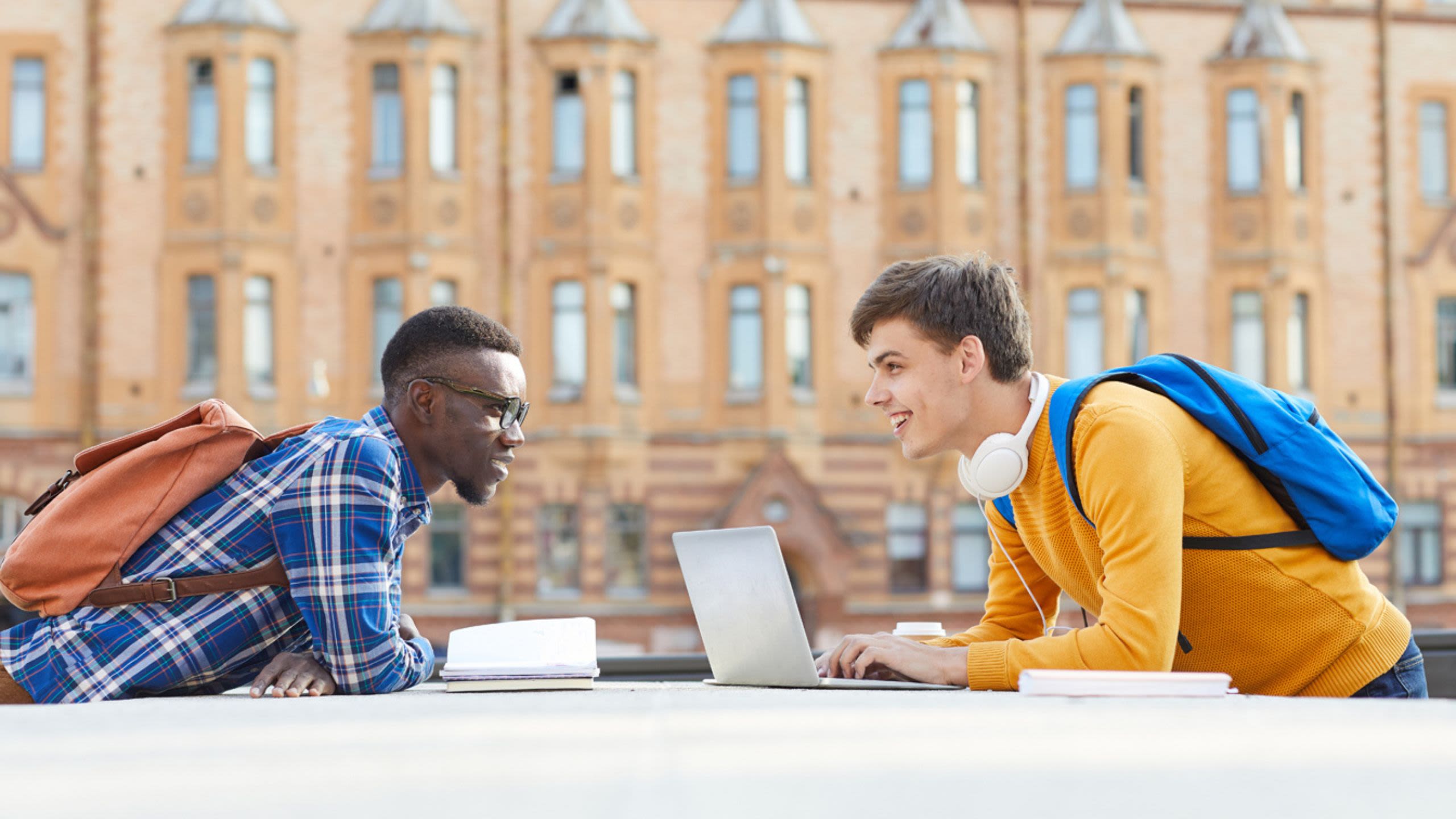 Two students looking over at eachother over laptop