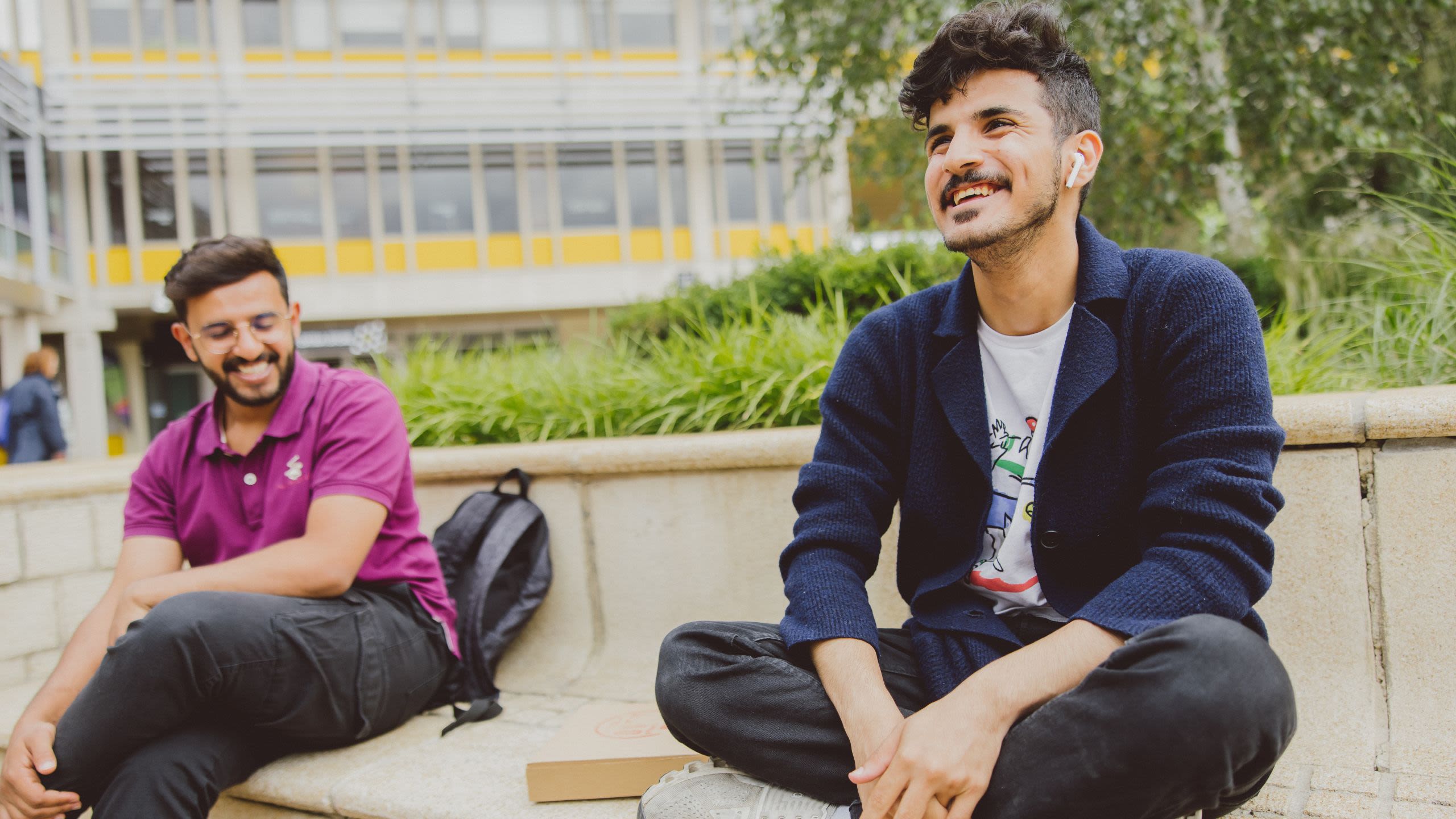 Two male students sitting on seats on campus