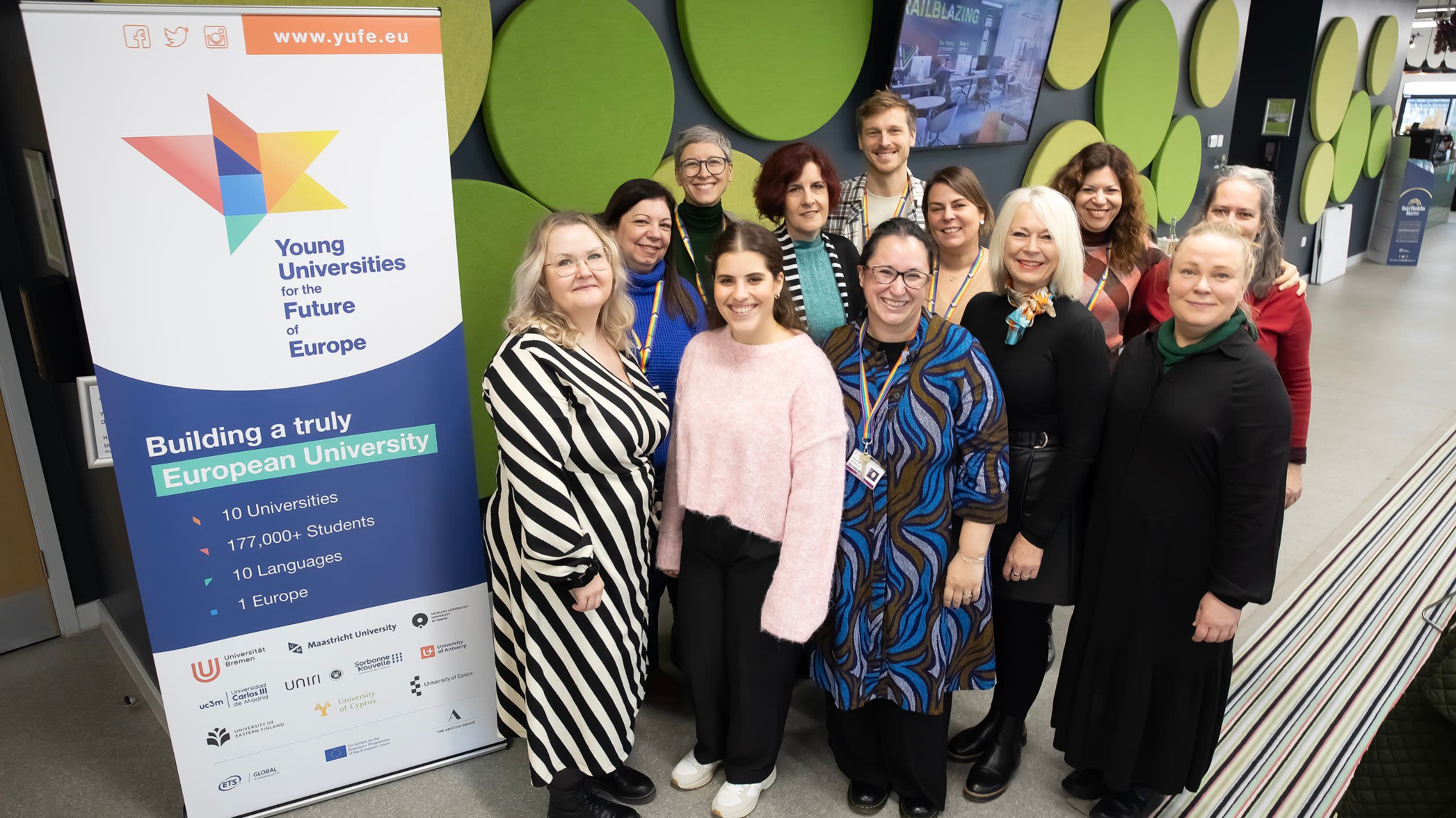 Group of YUFE staff beside YUFE banner