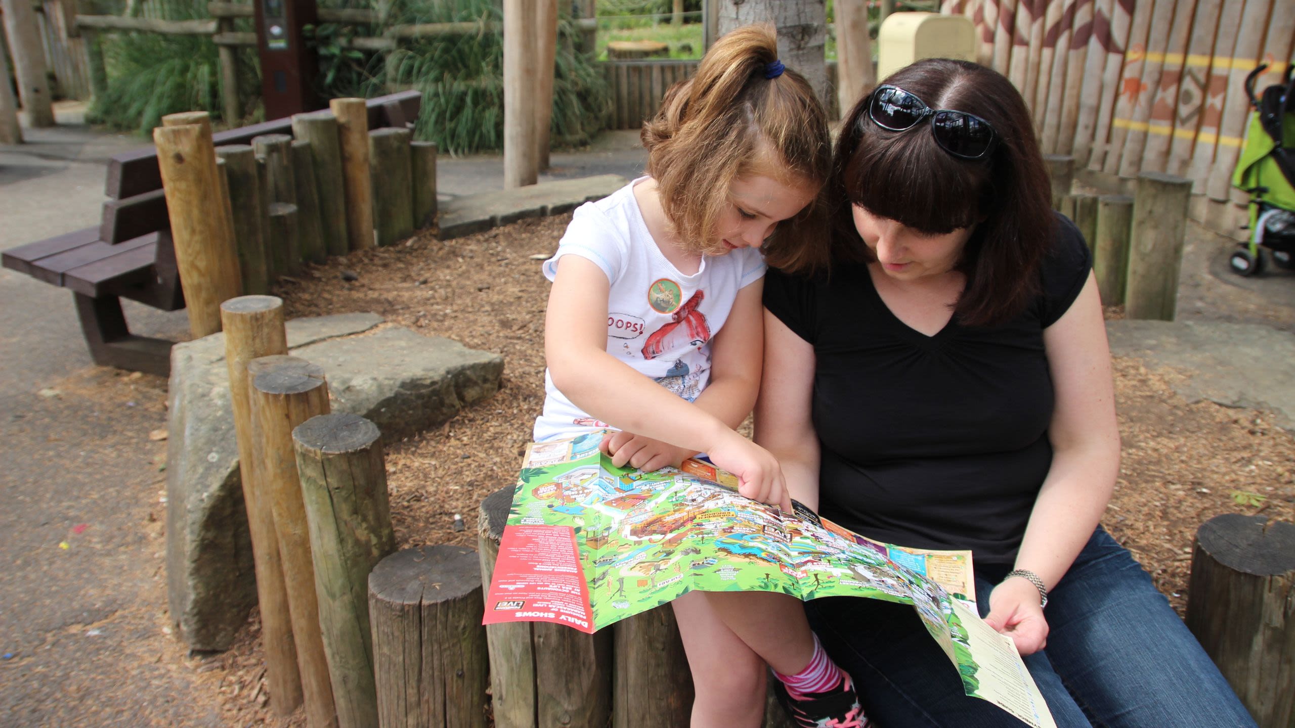 Mother and young daughter looking at map outside