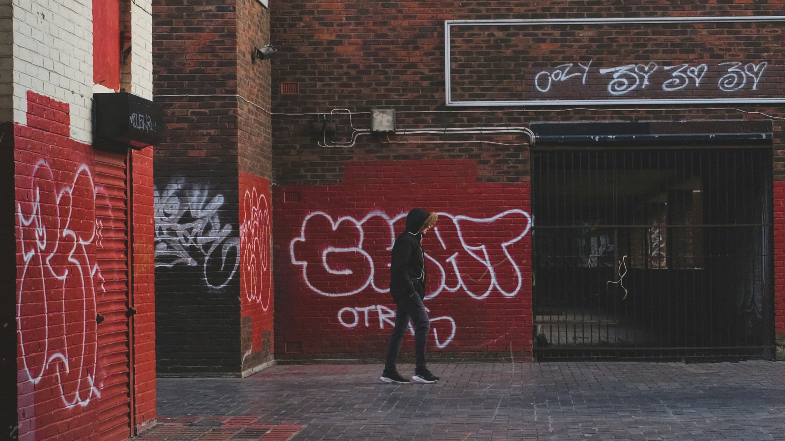 Person walking past a wall of graffiti