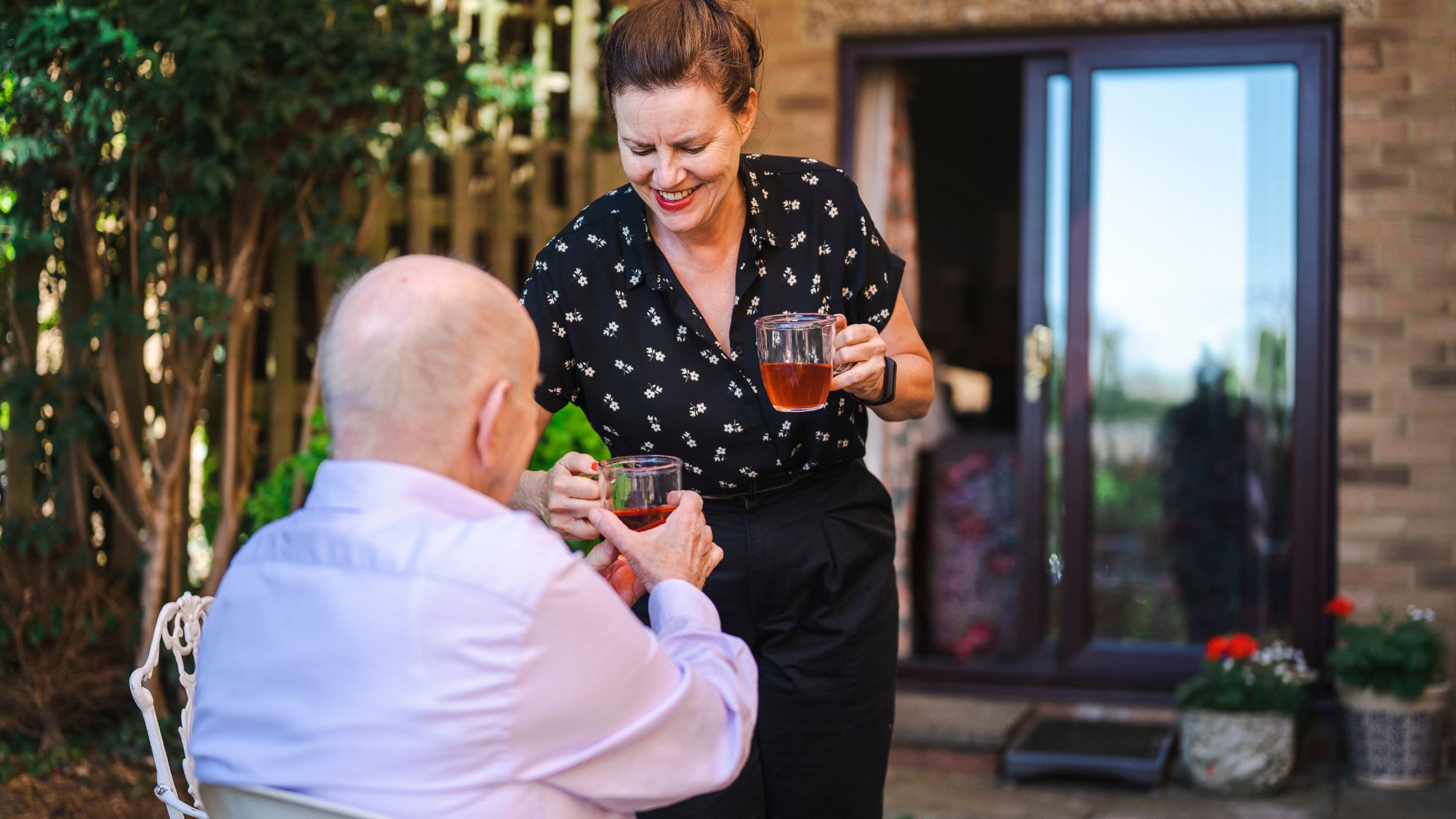 Older woman giving older ma a cup of tea