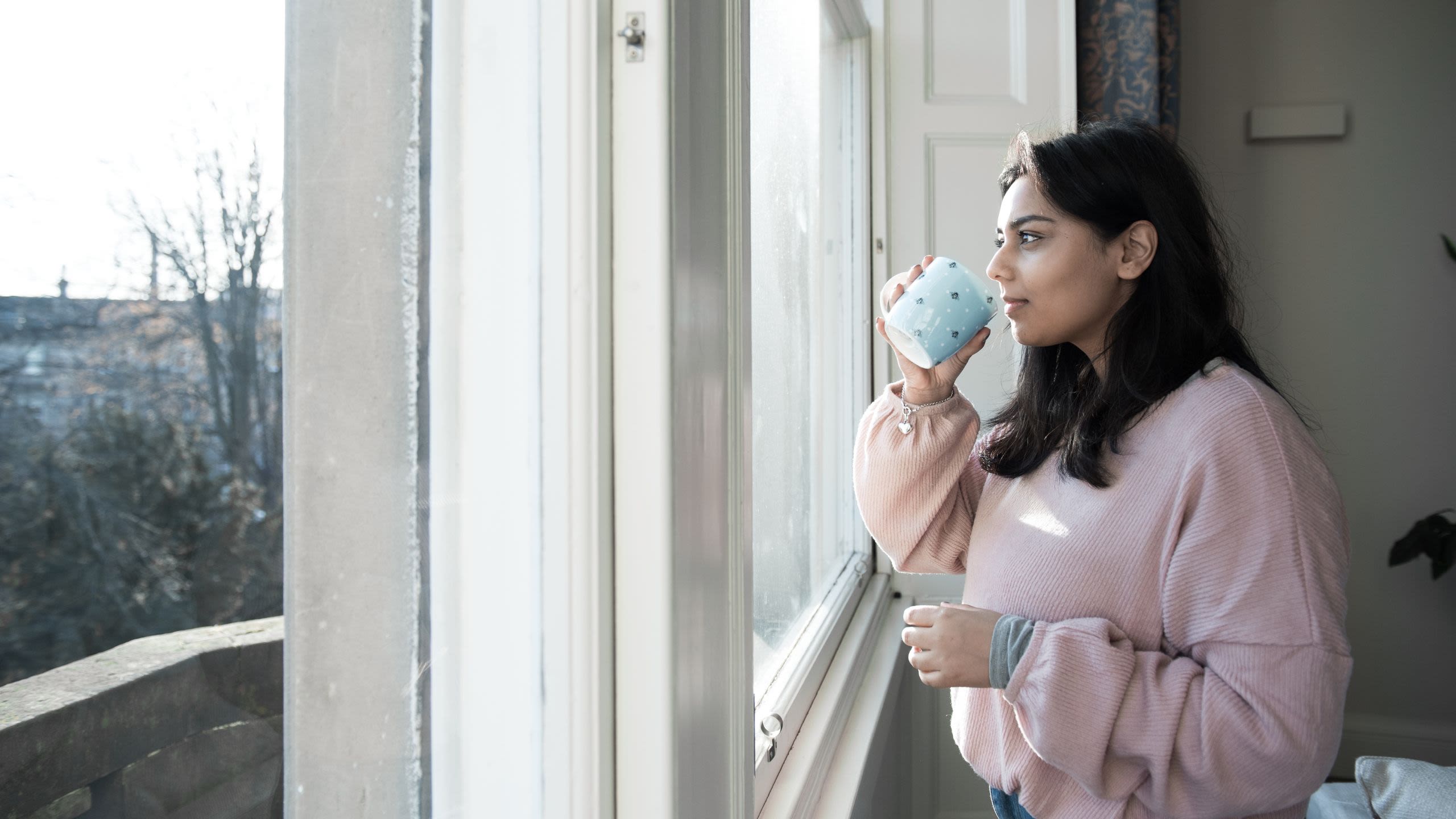 Woman drinking tea looking out of the window