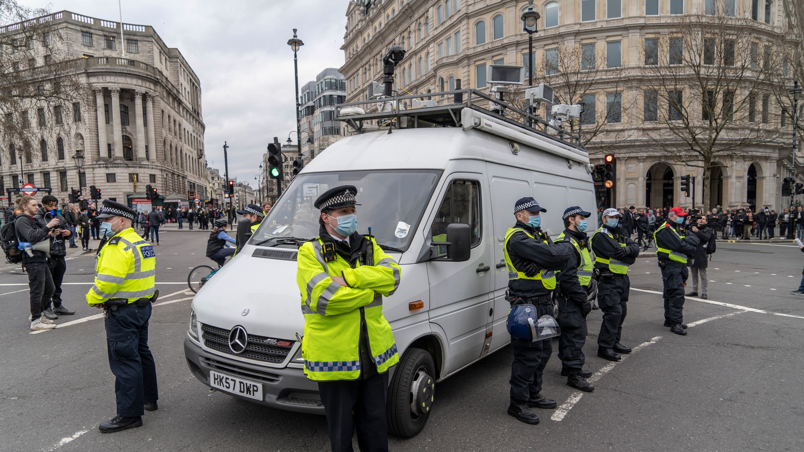 Police van with surveillance cameras on roof parked in middle of London street surrounded by police officers