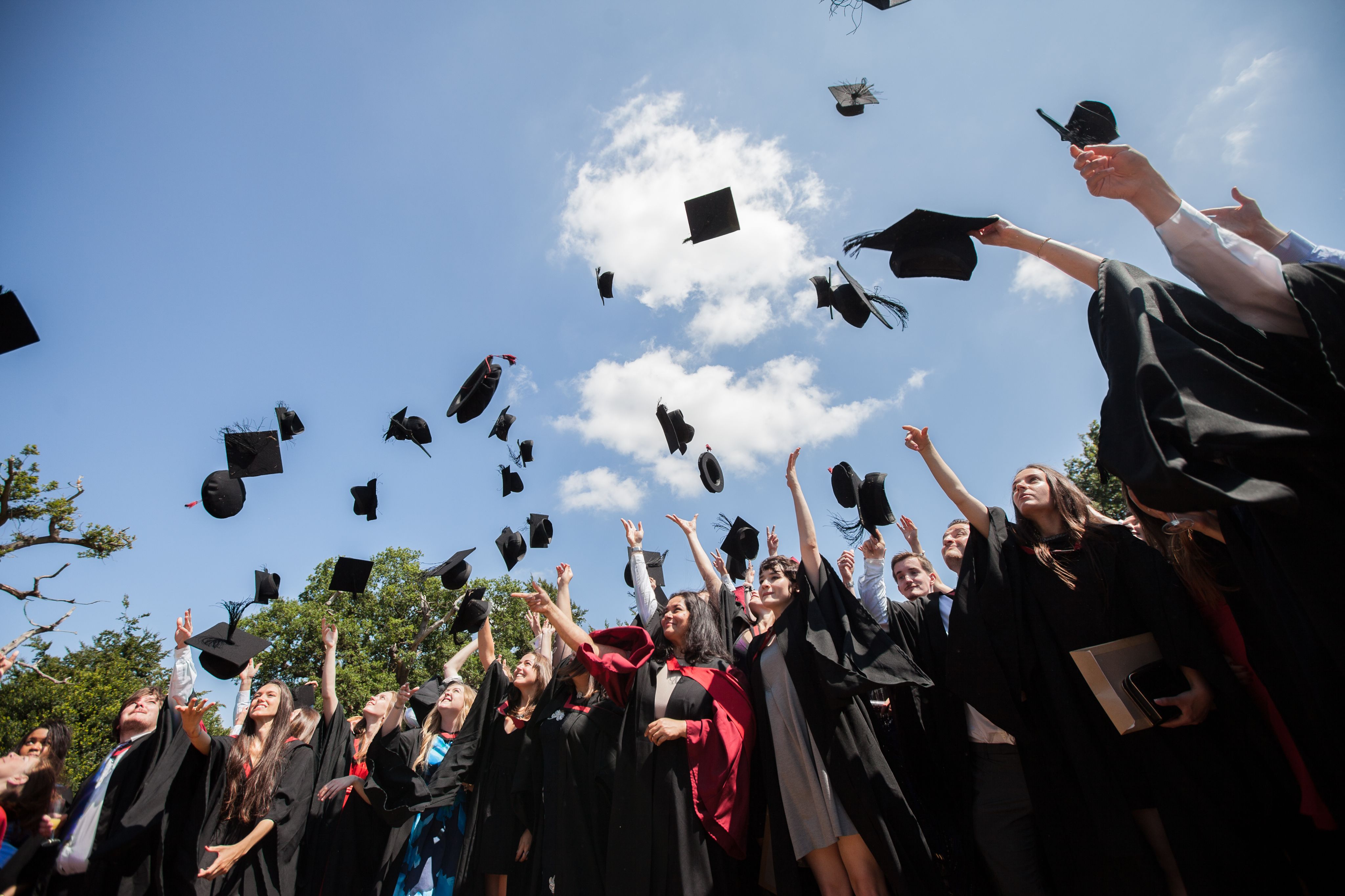 A group of graduates throw their mortarboards in the air