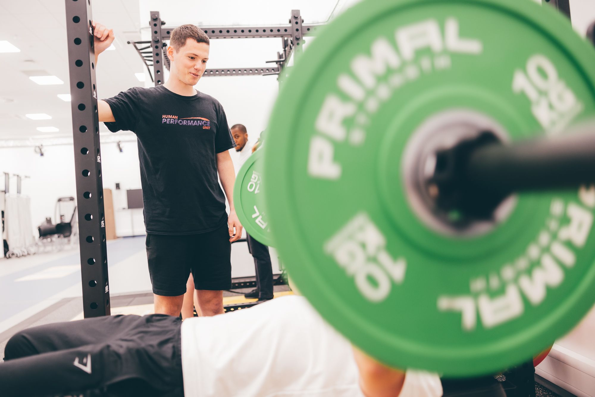 A member of the Human Performance Unit team supports a weightlifter