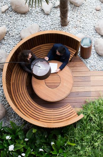 Two people, seen from above, sit in a circular wooden booth chatting