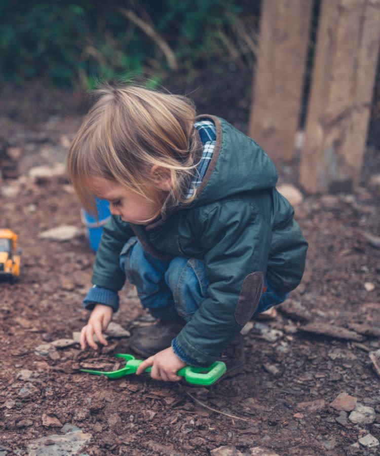Child playing with mud using aplastic spade