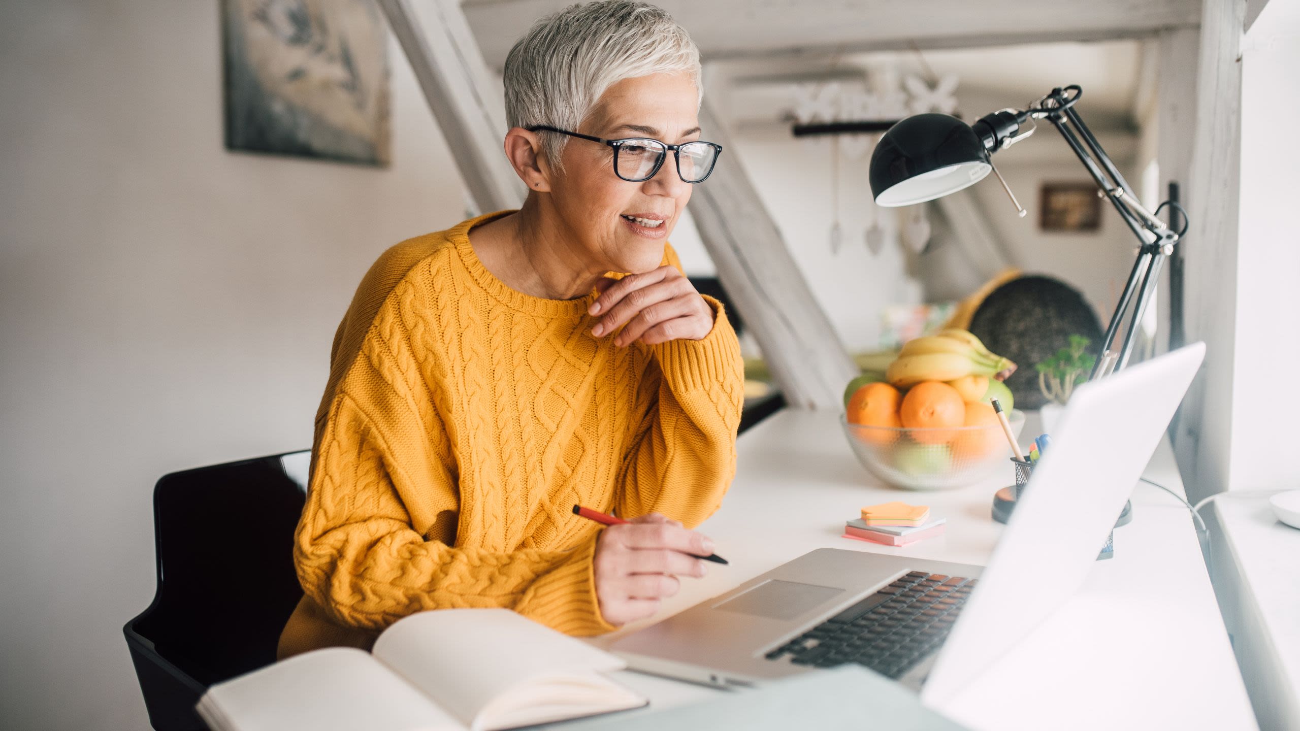 Woman in yellow jumper looking at laptop