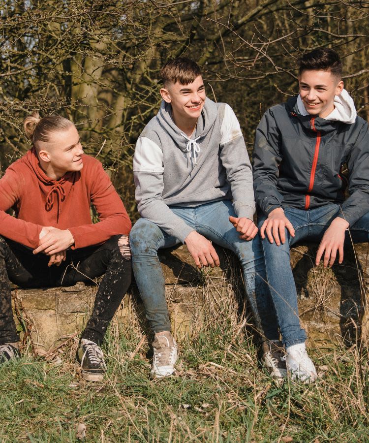 Three teenagers sitting outside chatting